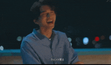 a man in a blue shirt is laughing with chinese writing on the bottom