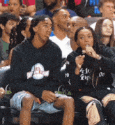 a boy wearing an atl dream team sweatshirt sits next to a girl