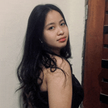 a young woman with long black hair is standing in front of a wooden door