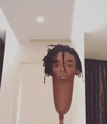 a man with dreadlocks and a nose ring is standing in a room with a prosthetic leg in front of him .