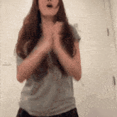a woman in a grey shirt is clapping her hands together
