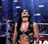 a woman is standing in a wrestling ring with her eyes closed and a crowd behind her .