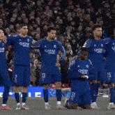 a group of soccer players wearing qatar airways jerseys stand on the field