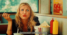a woman sitting at a table with a bucket of ketchup and mustard and a sign that says 99 on it
