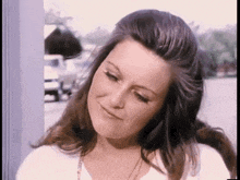 a close up of a woman 's face with long hair and a white shirt .