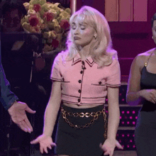 a woman in a pink crop top and black skirt is standing on a stage