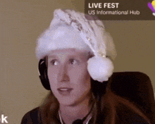 a woman wearing a santa hat is sitting in front of a sign that says live fest