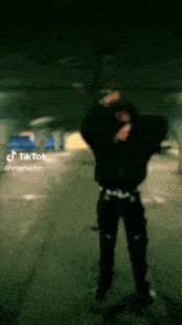 a man in a black hoodie is dancing in a dark room with a tiktok watermark