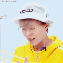 a person wearing a yellow jacket and a white hat with the word tropicalsweet written on the bottom