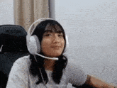 a woman wearing headphones with a microphone on her head is sitting in a chair that says 2uxer