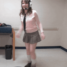 a woman wearing headphones and a pink sweater is standing in a room