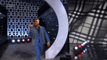 a man in a blue suit giving the middle finger in front of a tv