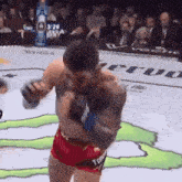 a man in red shorts is boxing in a ring with a monster energy drink in the background .
