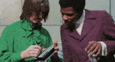 a man in a purple suit and a woman in a green shirt are working on a machine