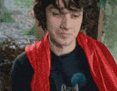 a man is wearing a red cape and a black shirt with a wolf on it