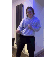 a man wearing a white hoodie with the word north face on it is dancing in front of a blue wall
