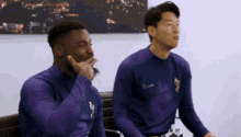 two soccer players are sitting on a bench in front of a spurs tv logo