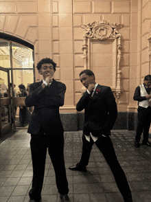 a man in a tuxedo stands next to another man in a tuxedo