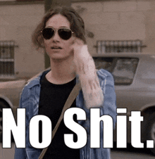 a woman wearing sunglasses and a denim jacket says no shit