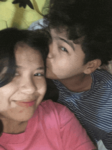 a boy kisses a girl on the cheek and the girl is smiling