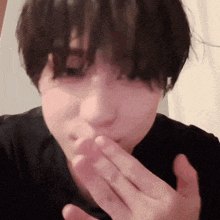 a person with short hair is covering their mouth with their hand