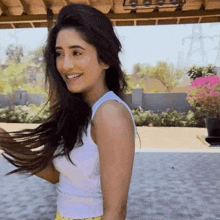 a woman wearing a white tank top is smiling