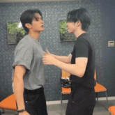 two young men are hugging each other in a room with chairs .