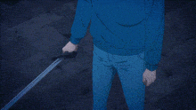 a man in a blue hoodie is holding a sword in his hand in a dark room .
