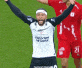 a soccer player wearing a sports da sorte jersey holds his arms up in the air