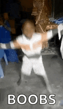 a man in a white shirt and shorts is dancing in a room with the words `` boobs '' written on the bottom .