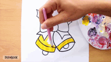 a person is painting a bell on a piece of paper that says drawbook on the bottom