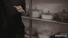 a person is standing in front of a shelf full of pots and pans with the words made in animatica on the bottom right