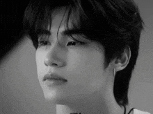 a black and white photo of a young man 's face with a piercing in his ear .