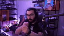 a man with a beard and glasses is sitting in a chair in a room .