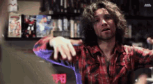 a man in a plaid shirt is standing in front of a shelf with a sign that says ' a ' on it