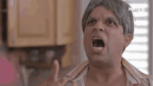 a man with gray hair and a wig is making a funny face with a foreign language written above him