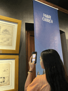 a woman taking a picture of a paoay church sign