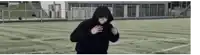 a man wearing a black hoodie is standing on a soccer field .