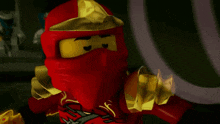 a close up of a lego ninjago character with a red helmet and gold armor .