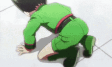a man in a green uniform is kneeling down on the floor .