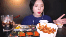 a woman wearing headphones is eating a tray of food with a spoon in her mouth