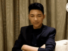a man in a suit is sitting on a couch with his arms crossed