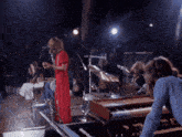 a woman in a red dress is singing into a microphone on stage
