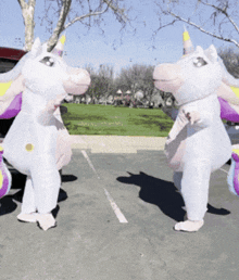 two inflatable unicorns are standing in a parking lot