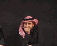 a man in a black shirt and a red and white checkered head scarf