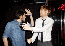 two men giving each other a high five in front of a neon sign