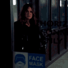 a woman stands in front of a glass door with a sign that says face mask