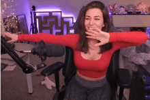a woman in a red crop top is sitting in front of a microphone