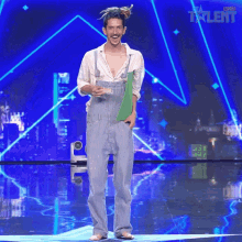 a man in overalls stands on a stage in front of a sign that says spain talent