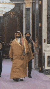 a man in a tan robe is walking in a hallway